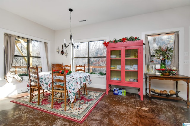 dining area featuring concrete flooring, a wealth of natural light, and a notable chandelier