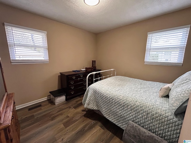 bedroom with a textured ceiling, dark hardwood / wood-style floors, and multiple windows