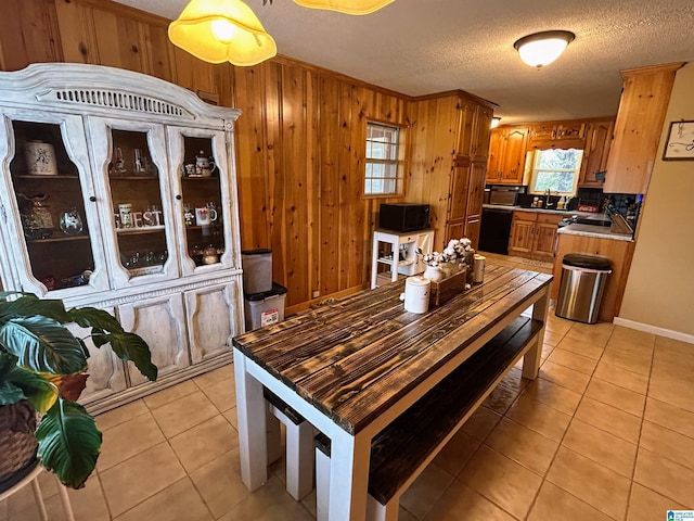 dining area with wooden walls, light tile patterned flooring, and a textured ceiling