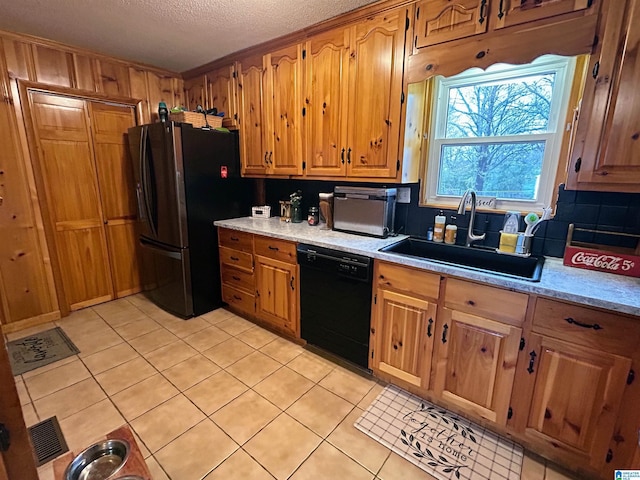 kitchen featuring light tile patterned flooring, a textured ceiling, sink, and black appliances