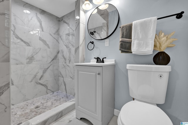 bathroom with vanity, toilet, and tiled shower