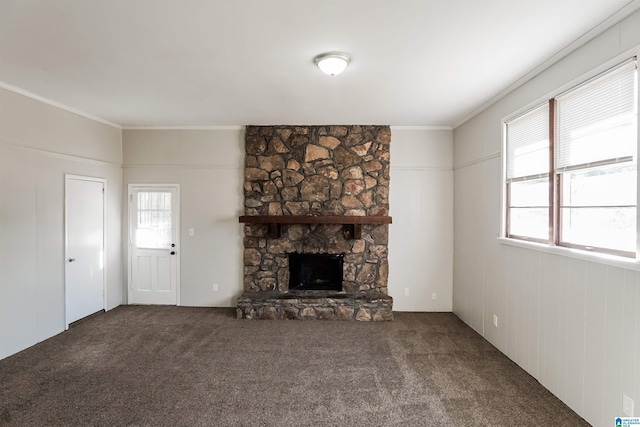 unfurnished living room with a stone fireplace, crown molding, and carpet floors