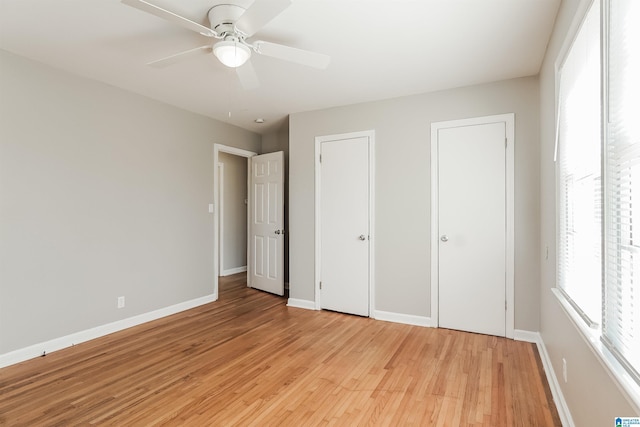 unfurnished bedroom with ceiling fan, light hardwood / wood-style floors, and two closets