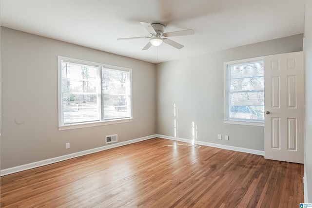 empty room featuring hardwood / wood-style flooring, ceiling fan, and a healthy amount of sunlight