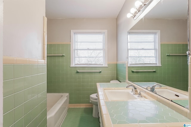 bathroom featuring vanity, a bathtub, toilet, and tile walls