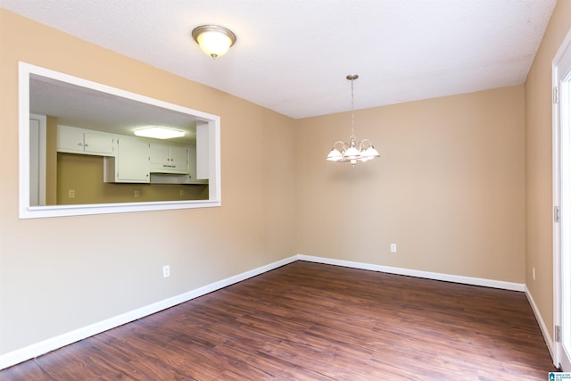 unfurnished room with hardwood / wood-style flooring, a textured ceiling, and a notable chandelier