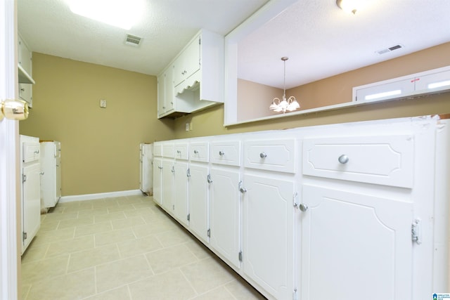 kitchen with hanging light fixtures, white cabinets, a chandelier, a textured ceiling, and light tile patterned floors