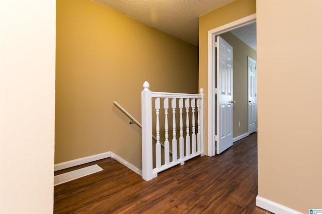 corridor featuring dark hardwood / wood-style flooring and a textured ceiling