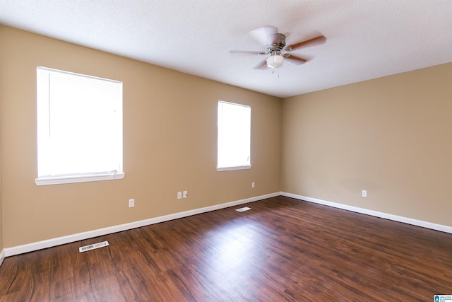 spare room with a textured ceiling, ceiling fan, and dark hardwood / wood-style floors