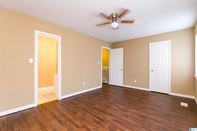 unfurnished bedroom featuring a textured ceiling, ceiling fan, dark hardwood / wood-style floors, and ensuite bathroom