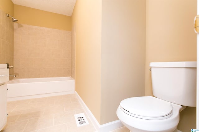 bathroom with tiled shower / bath, a textured ceiling, and toilet