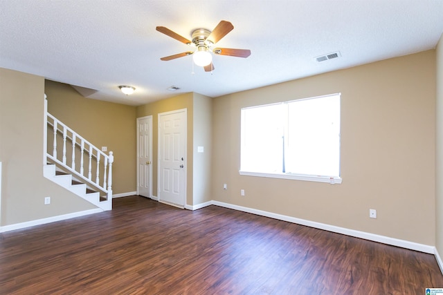 empty room with ceiling fan, dark wood-type flooring, and a textured ceiling