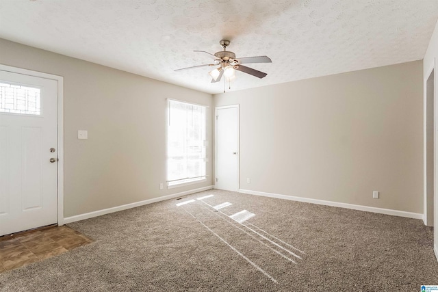 carpeted foyer entrance featuring ceiling fan and a textured ceiling