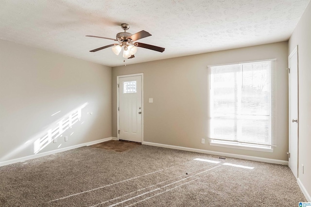 foyer entrance with carpet flooring, ceiling fan, and a textured ceiling