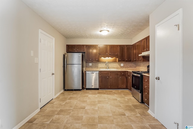 kitchen with backsplash, sink, stainless steel appliances, and a textured ceiling