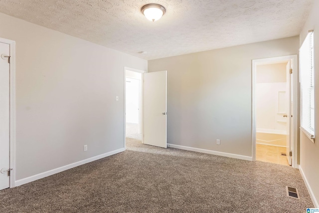 unfurnished bedroom featuring carpet, a textured ceiling, and ensuite bath