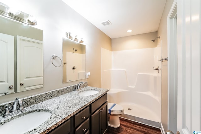 bathroom with hardwood / wood-style floors, vanity, toilet, and walk in shower