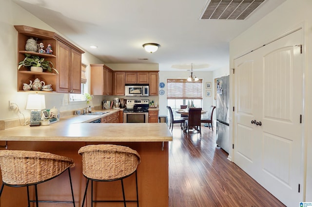 kitchen with a healthy amount of sunlight, a kitchen bar, kitchen peninsula, and stainless steel appliances