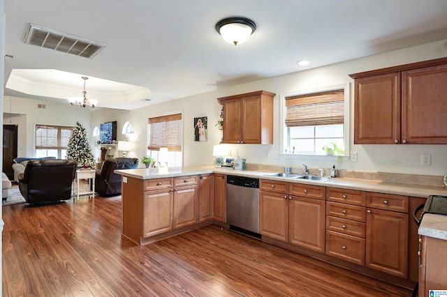 kitchen with hanging light fixtures, stainless steel dishwasher, dark hardwood / wood-style floors, a tray ceiling, and kitchen peninsula