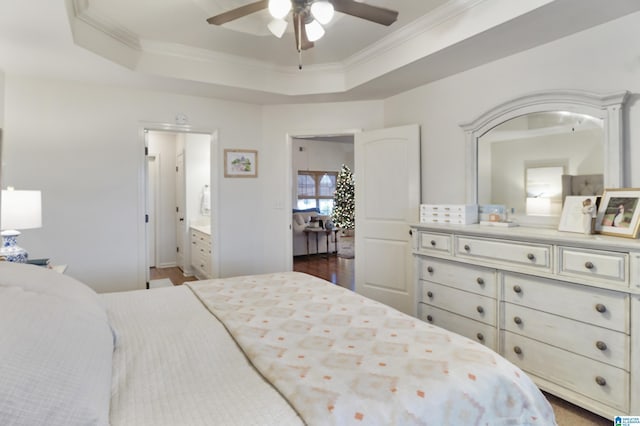 bedroom with a tray ceiling, connected bathroom, ceiling fan, and dark wood-type flooring