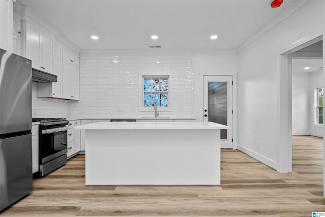 kitchen featuring white cabinetry, a center island, sink, black gas range oven, and stainless steel fridge