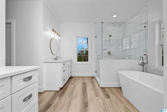 bathroom featuring vanity, hardwood / wood-style flooring, separate shower and tub, and ornamental molding