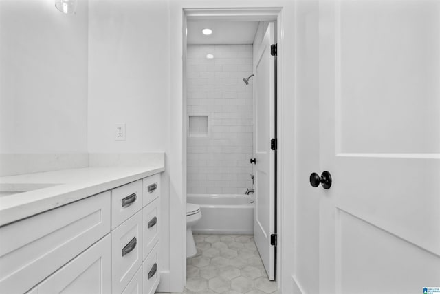 full bathroom with tile patterned flooring, vanity, tiled shower / bath combo, and toilet