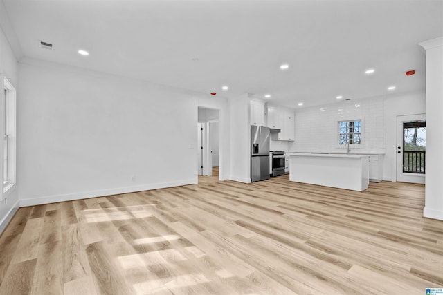 unfurnished living room featuring crown molding, sink, and light wood-type flooring