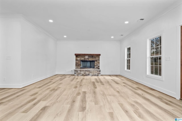 unfurnished living room featuring a stone fireplace, crown molding, and light wood-type flooring