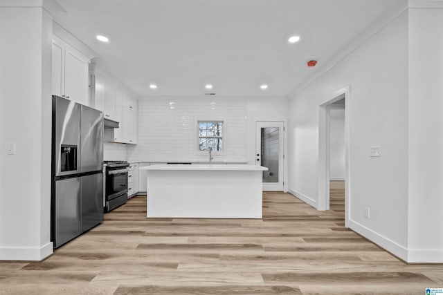 kitchen featuring light hardwood / wood-style flooring, appliances with stainless steel finishes, tasteful backsplash, a kitchen island, and white cabinetry