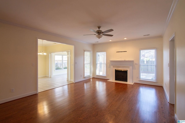 unfurnished living room with hardwood / wood-style floors, ceiling fan with notable chandelier, and ornamental molding