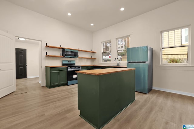 kitchen featuring a center island, stainless steel appliances, wood counters, green cabinets, and light hardwood / wood-style floors