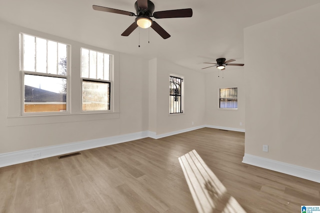 spare room featuring light hardwood / wood-style floors, ceiling fan, and a healthy amount of sunlight