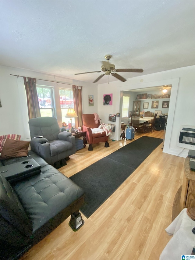 living room featuring heating unit, ceiling fan, and wood-type flooring