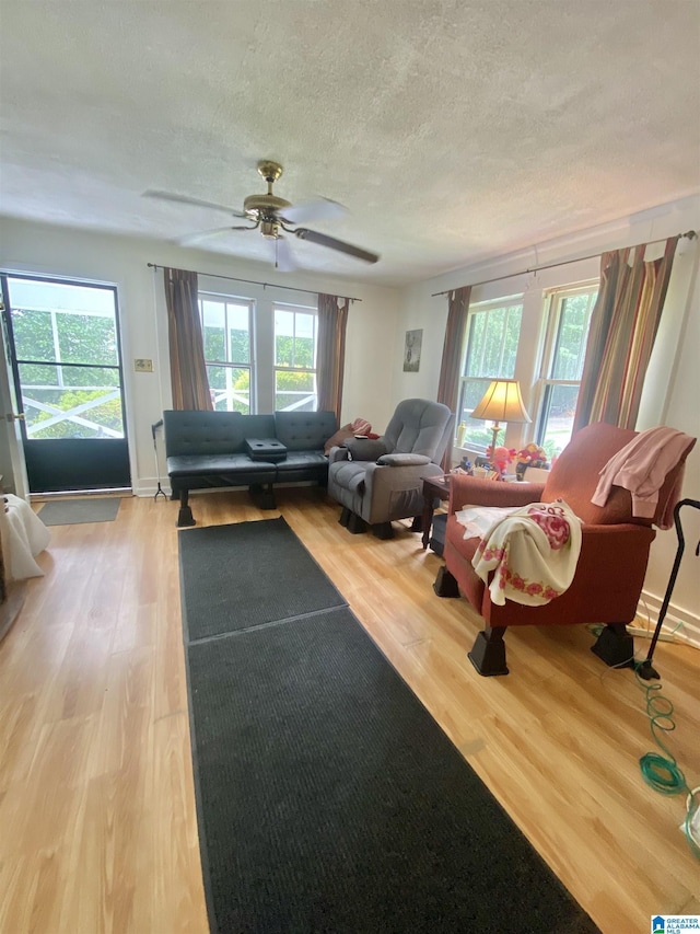 living room featuring a textured ceiling, light hardwood / wood-style floors, and ceiling fan