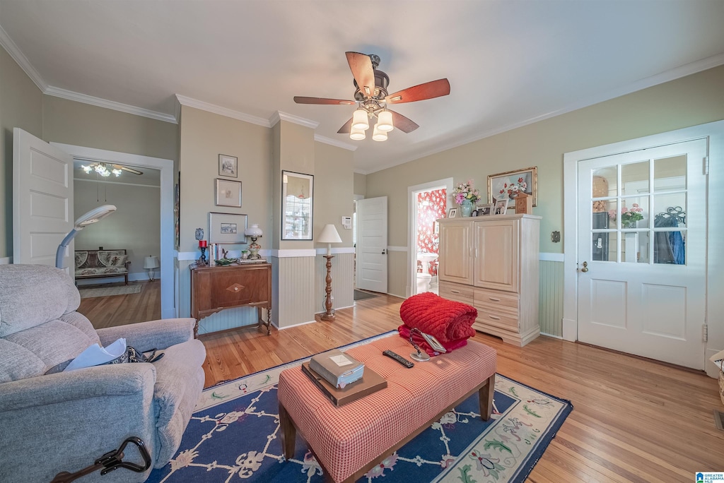 living room with ceiling fan, crown molding, and light hardwood / wood-style floors