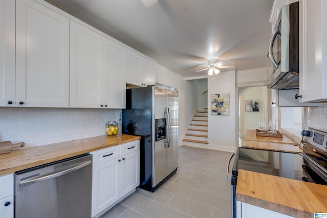 kitchen with appliances with stainless steel finishes, backsplash, ceiling fan, white cabinets, and butcher block countertops