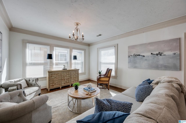 living room featuring wood-type flooring, an inviting chandelier, a healthy amount of sunlight, and crown molding