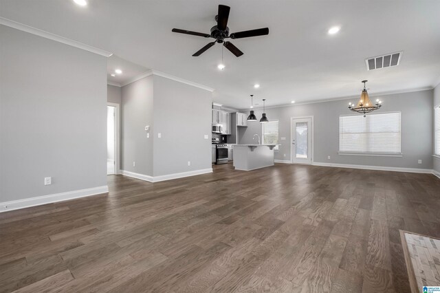 unfurnished living room with ceiling fan with notable chandelier, dark hardwood / wood-style floors, and crown molding