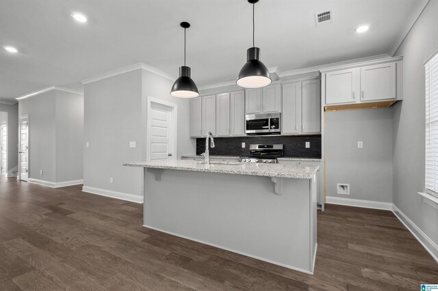 kitchen with pendant lighting, light stone countertops, a kitchen island with sink, and appliances with stainless steel finishes