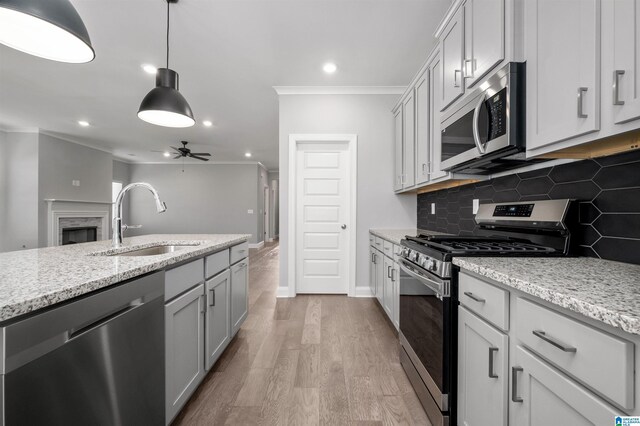 kitchen featuring ceiling fan, sink, light stone countertops, tasteful backsplash, and appliances with stainless steel finishes