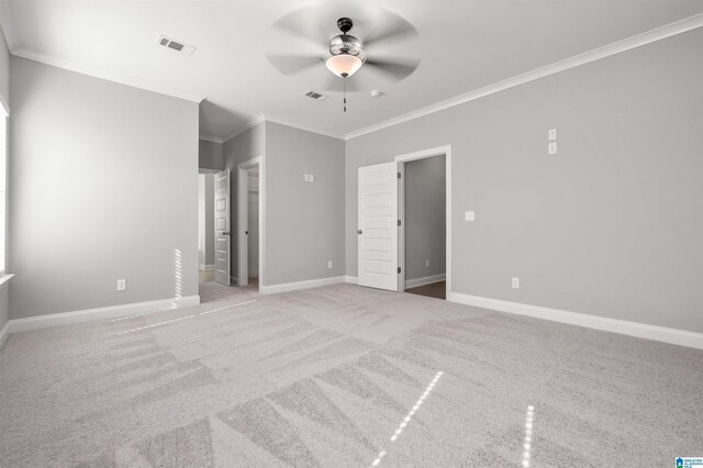 empty room featuring ceiling fan, crown molding, and light colored carpet