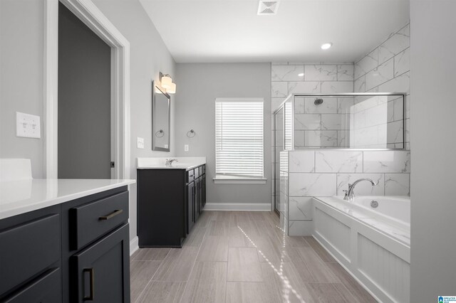 bathroom with vanity and shower with separate bathtub