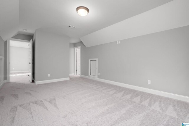 additional living space featuring light colored carpet and vaulted ceiling