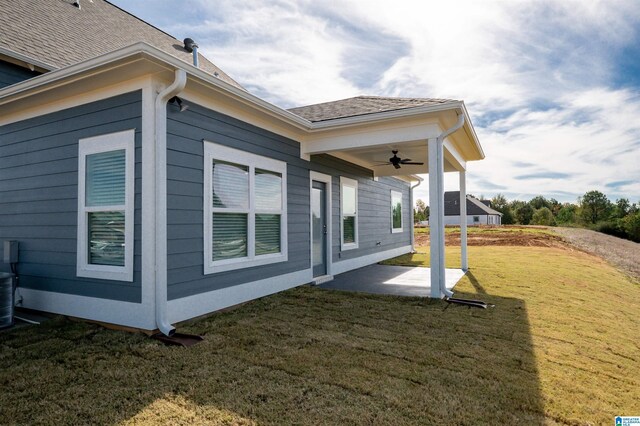 view of side of home featuring a yard, ceiling fan, and a patio area