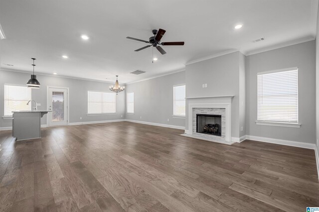 unfurnished living room with a wealth of natural light, dark wood-type flooring, and ceiling fan with notable chandelier