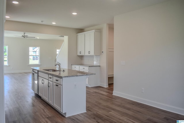 kitchen with sink, stainless steel dishwasher, light stone countertops, an island with sink, and white cabinetry