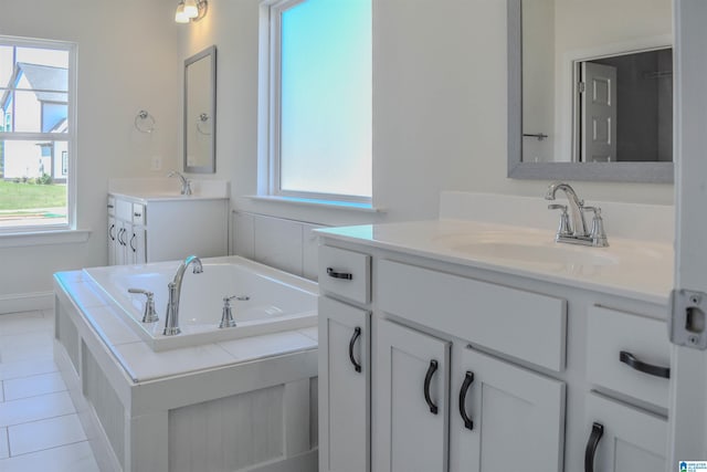 bathroom with vanity, tiled bath, and a healthy amount of sunlight