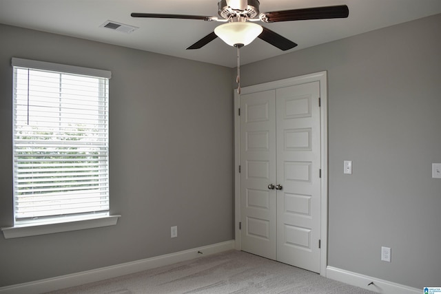 unfurnished bedroom featuring light carpet, a closet, and ceiling fan