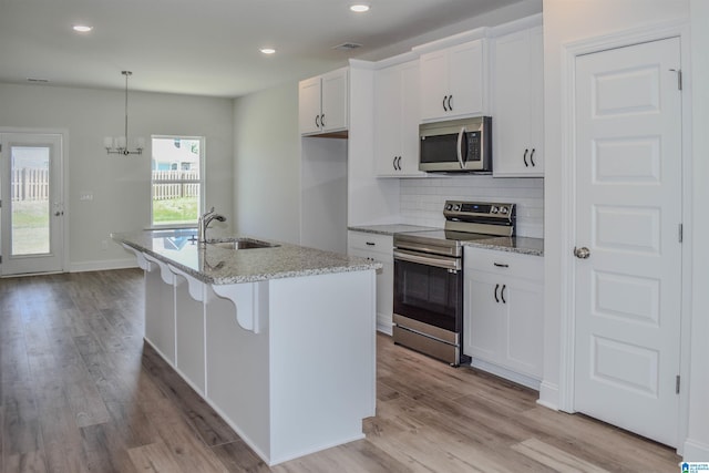 kitchen featuring a kitchen island with sink, sink, white cabinets, and appliances with stainless steel finishes